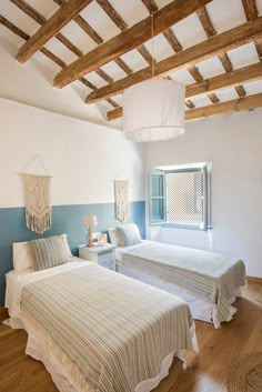 two beds in a room with wooden floors and beams on the ceiling are made of wood