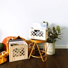 a wooden table topped with boxes next to a potted plant on top of a hard wood floor