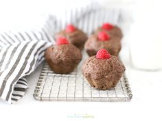 chocolate muffins with raspberries on a cooling rack next to a glass of milk