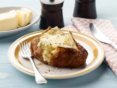 a plate with some food on it next to a fork and cup full of butter