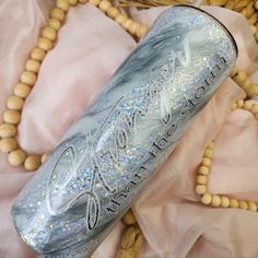 a blue and silver glittered bottle sitting on top of a wooden bead necklace