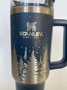 a stainless steel travel mug with the name stanley since 1915 printed on it and pine trees