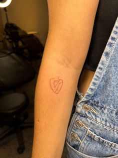 a woman's arm with a small tattoo in the shape of a heart on it