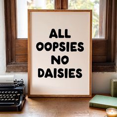 an old typewriter sitting next to a sign that says all oppsies no daisies