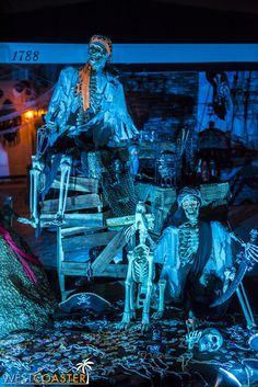 an outdoor display with skeletons and skeletons in the night time, including a man sitting on a chair