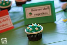 cupcakes with green frosting and white sprinkles are on a table