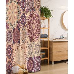 a bathroom with a shower curtain that has an intricate pattern on it, and a plant in the corner