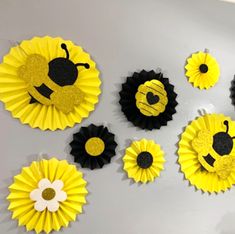 yellow and black paper flowers are arranged on the wall in front of a white wall