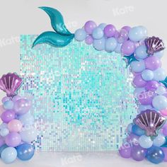 the mermaid balloon arch is decorated with blue, purple and lavender balloons as well as little mermaid tails