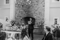 a man giving a speech in front of a group of people at a wedding reception