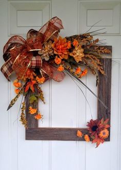 a wooden frame decorated with fall flowers and leaves is hung on the door to display an autumn wreath