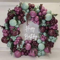 a birthday wreath made out of balloons and greenery