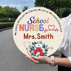 a woman holding up a wooden sign that says school nurse and mrs smith on it