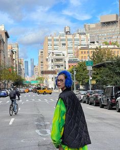 a woman with blue hair standing in the middle of an empty city street, looking off into the distance