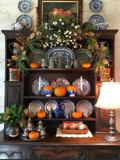 an old china cabinet with plates and pumpkins on it