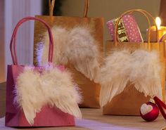 three small bags with feathers on them sitting on a table next to candles and decorations