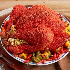 a large meat covered in red sauce on a plate with peppers and other food items