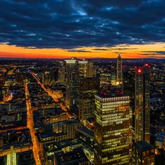 the city skyline is lit up at night with bright lights and clouds in the sky