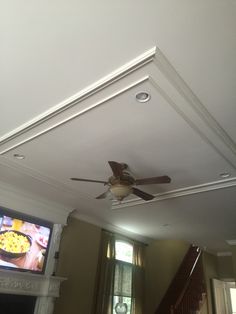 a ceiling fan is hanging from the ceiling in front of a fireplace and television screen