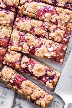 berry crumble bars cut into squares on top of a cutting board with a knife