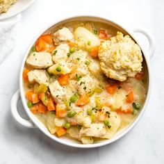 a bowl filled with chicken and dumplings on top of a white counter next to another bowl