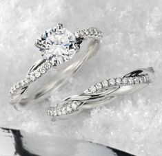 two white gold wedding rings with diamonds in them on snow covered ground next to each other