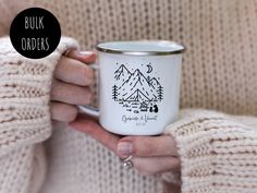 a woman holding a white coffee mug with a mountain scene printed on the front and bottom