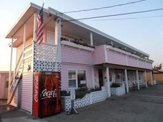 a pink building with an american flag on the balcony and coca - cola machine in front