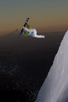 a man flying through the air while riding skis on top of a snow covered slope