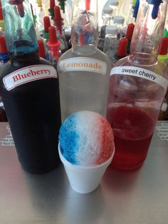 three different colored drinks sitting on top of a table next to bottles and glasses filled with liquid