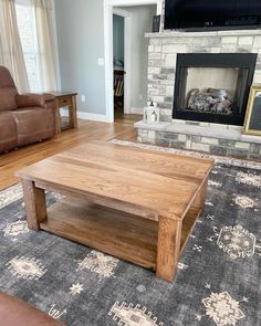 a living room with a couch, coffee table and fireplace in it's center