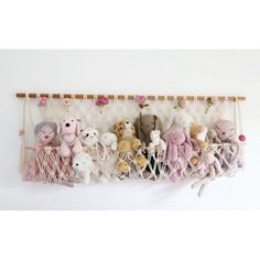 several stuffed animals are hanging in a hammock with flowers on the wall behind them