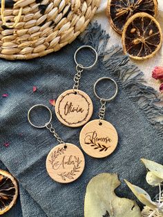 three wooden keychains with names on them sitting next to some dried oranges