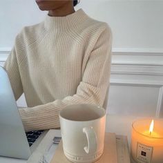 a woman sitting in front of a laptop computer with a candle on the desk next to her