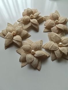 four pieces of fabric with flowers and pearls on top of each other, sitting on a white surface