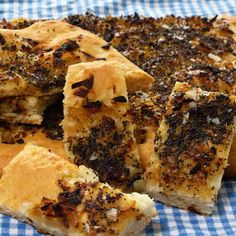 there are several pieces of bread that have been cut into squares on a blue and white checkered table cloth