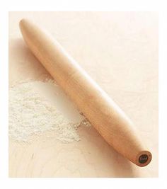 a wooden rolling pin sitting on top of a white table next to a pile of flour