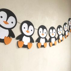 a group of penguins hanging from a line on a wall with clothes pins attached to them