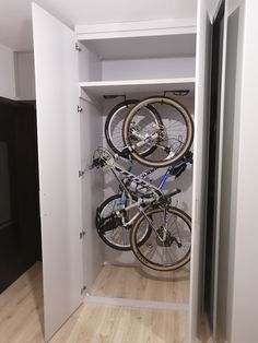 there are two bikes in the closet and one is on the bike rack with wheels