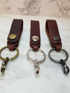 three leather keychains sitting on top of a marble counter