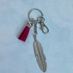 a feather keychain with a red tassel hanging from it's side