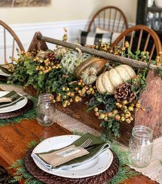 the table is set for thanksgiving dinner with pine cones, pumpkins and gourds