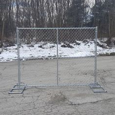 a chain link fence in the middle of a parking lot with snow on the ground