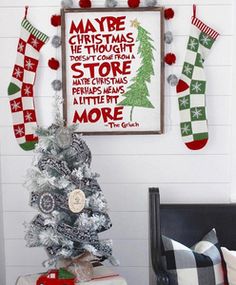 a christmas tree with stockings hanging on the wall next to it and a framed poster