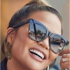 a woman wearing sunglasses and smiling for the camera