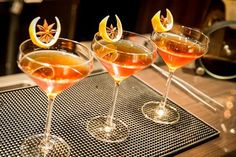 three glasses filled with drinks sitting on top of a table