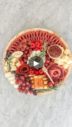 a platter filled with meats, cheeses and other foods on top of a marble table