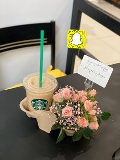 a cup of coffee and some flowers on a table with a sign that says starbucks