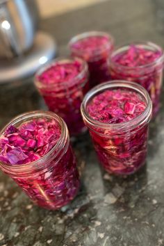 four jars filled with pink flowers sitting on top of a counter