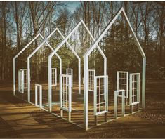 an outdoor play structure with multiple windows in the shape of houses, surrounded by trees